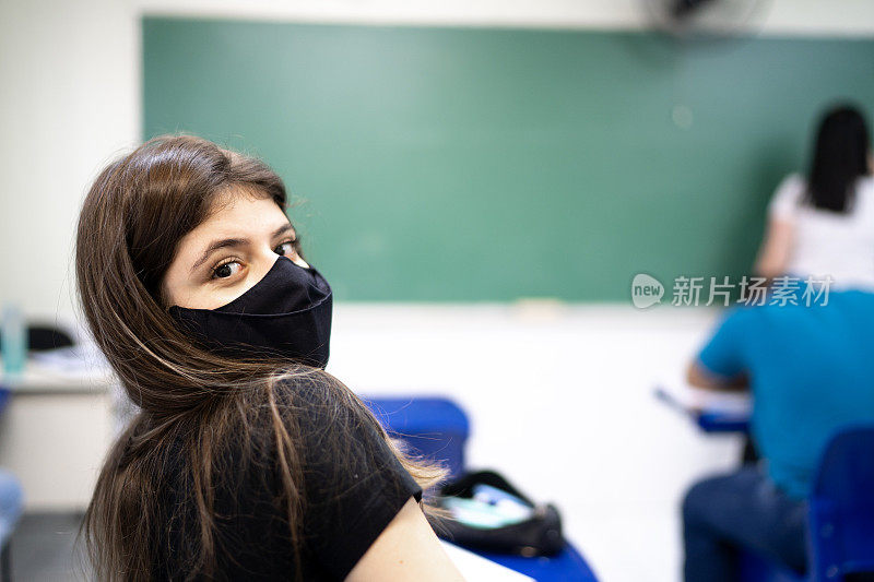 一个大学/高中学生戴着口罩在教室里的肖像